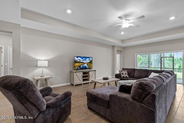 living room with a raised ceiling and ceiling fan