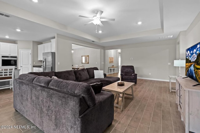 living room featuring ceiling fan and a tray ceiling