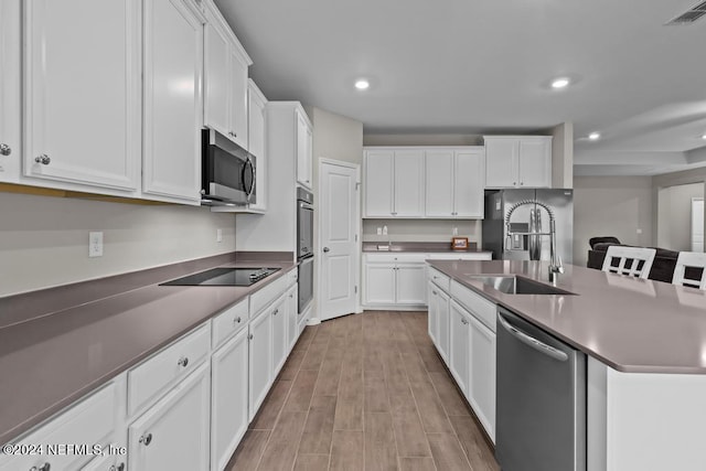 kitchen featuring sink, white cabinetry, stainless steel appliances, and a kitchen island with sink