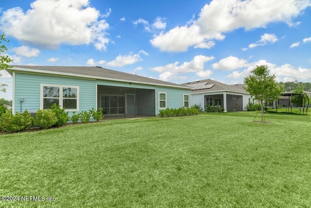 back of house featuring a yard, a trampoline, and a sunroom