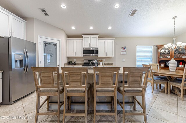 kitchen with white cabinetry, light tile patterned flooring, hanging light fixtures, and appliances with stainless steel finishes