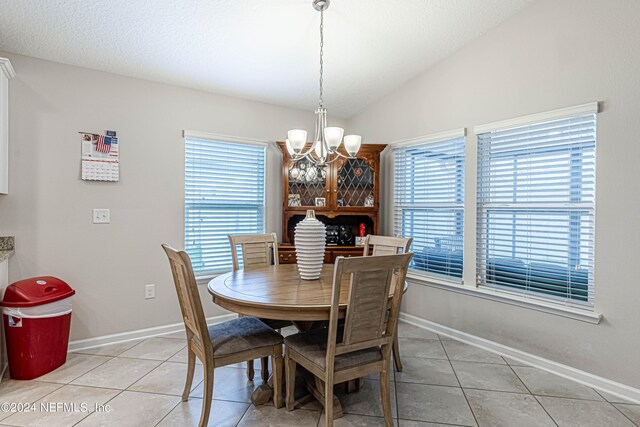 dining room with light tile patterned floors, lofted ceiling, and a notable chandelier