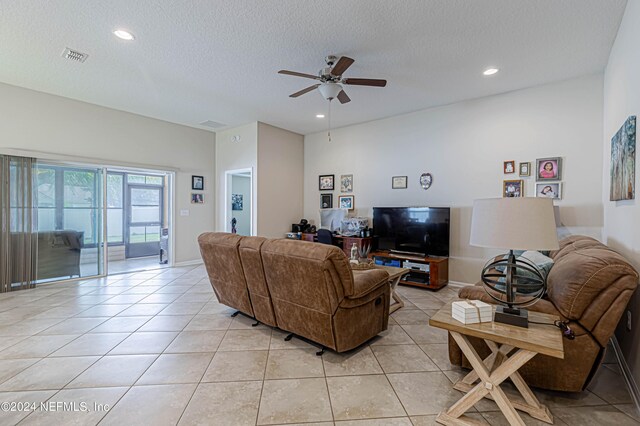 living room with ceiling fan, light tile patterned flooring, and a textured ceiling