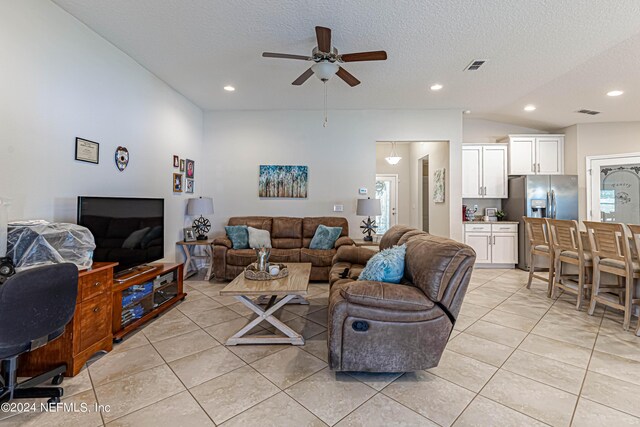 living room with ceiling fan, light tile patterned floors, and a textured ceiling