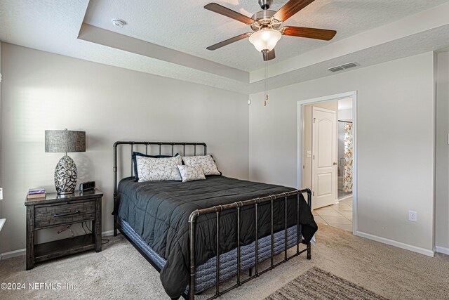 carpeted bedroom with a raised ceiling, ceiling fan, and a textured ceiling