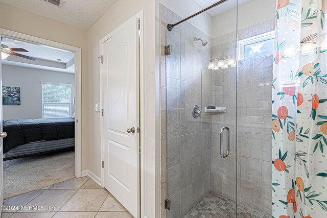 bathroom with a shower with shower curtain, ceiling fan, tile patterned floors, and a textured ceiling