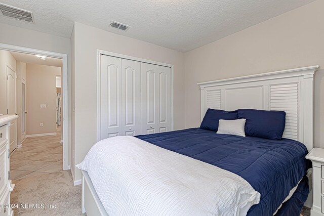 tiled bedroom featuring a textured ceiling and a closet