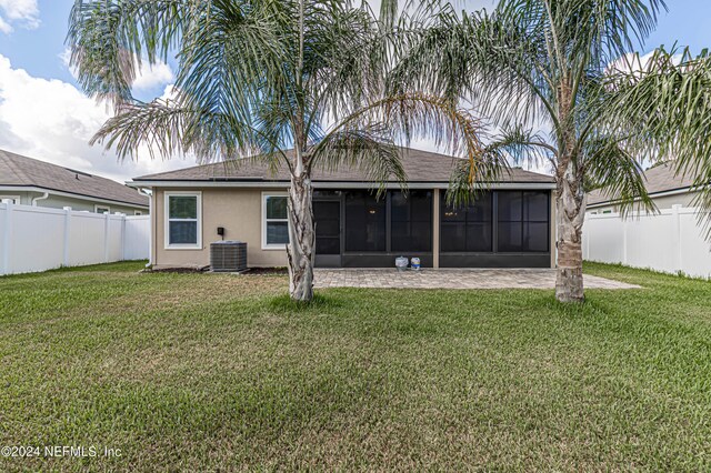 back of property with a sunroom, a yard, and central AC