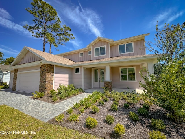 view of front of home featuring covered porch, french doors, and a garage