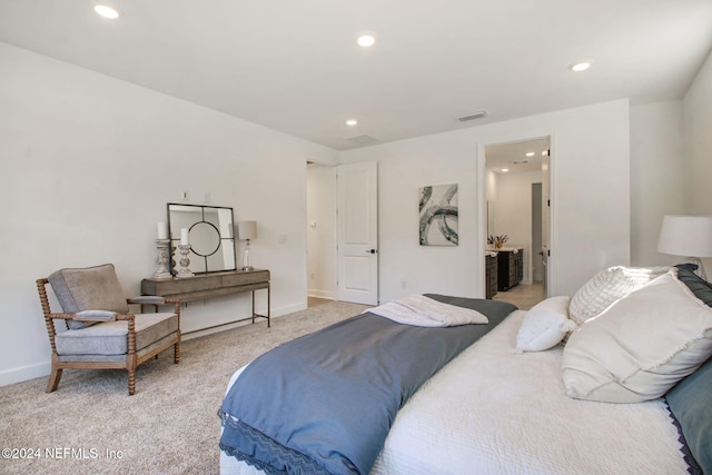 bedroom with ensuite bathroom and light colored carpet