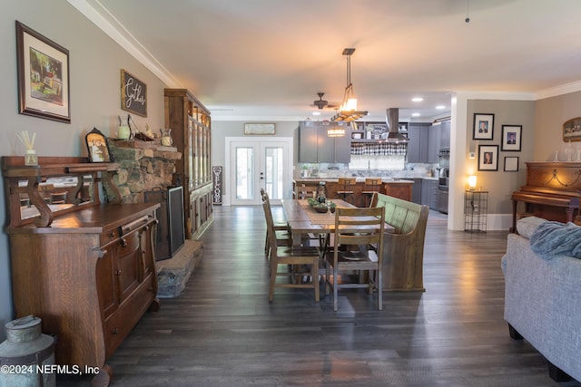 dining area with french doors, ornamental molding, dark hardwood / wood-style floors, and a stone fireplace