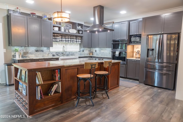 kitchen with hanging light fixtures, island exhaust hood, a center island, black appliances, and light stone countertops