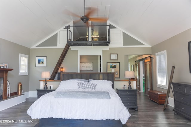 bedroom with a barn door, dark hardwood / wood-style floors, and high vaulted ceiling