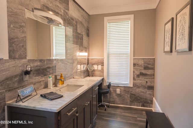 bathroom featuring hardwood / wood-style flooring, tile walls, vanity, ornamental molding, and a healthy amount of sunlight