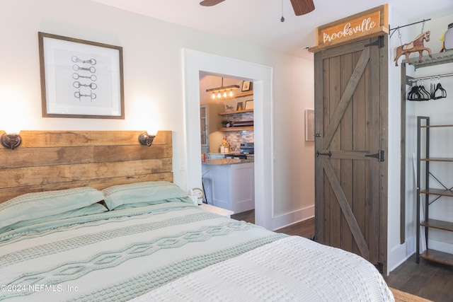 bedroom featuring dark hardwood / wood-style floors, a barn door, and ceiling fan