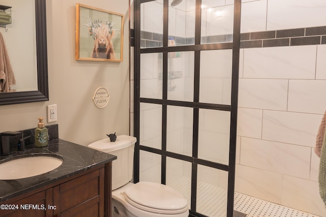 bathroom featuring a tile shower, vanity, and toilet