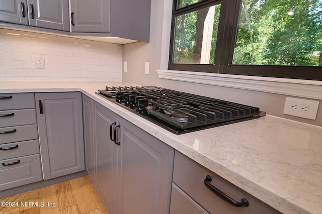 kitchen with gray cabinetry, gas stovetop, and light stone countertops