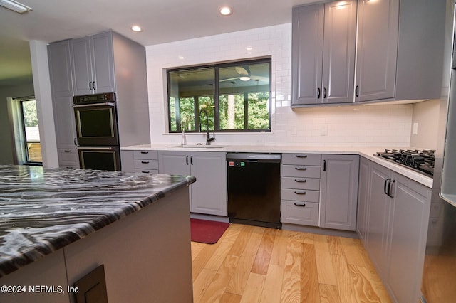 kitchen featuring sink, gray cabinetry, decorative backsplash, black appliances, and light hardwood / wood-style flooring