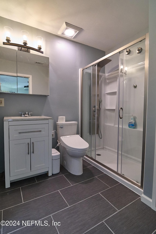 bathroom featuring a shower with door, vanity, and toilet