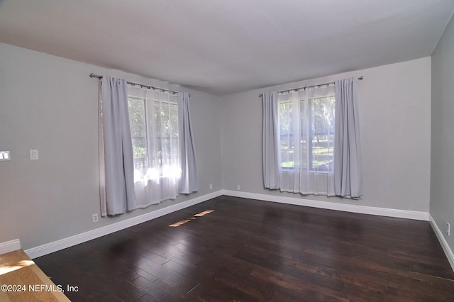 empty room with plenty of natural light and dark hardwood / wood-style flooring