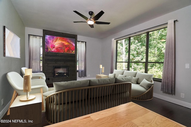 living room featuring a fireplace, dark wood-type flooring, and ceiling fan