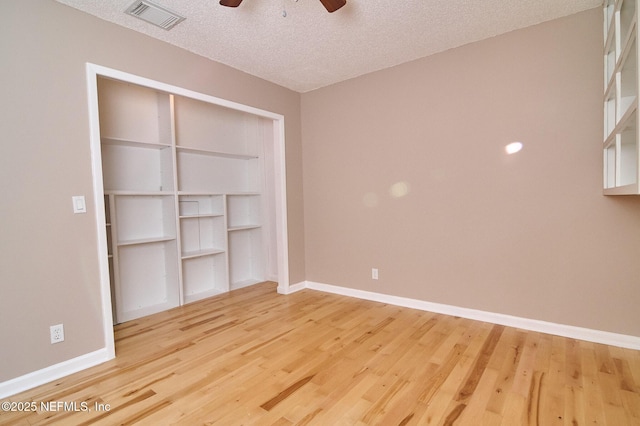 unfurnished bedroom with ceiling fan, wood-type flooring, a closet, and a textured ceiling