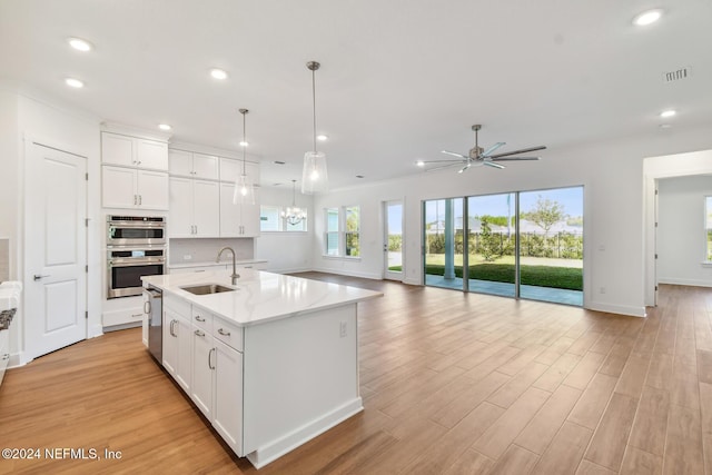 kitchen featuring ceiling fan, white cabinetry, sink, and a kitchen island with sink