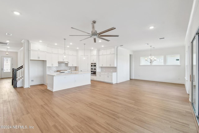 unfurnished living room with light hardwood / wood-style flooring, ceiling fan with notable chandelier, and sink