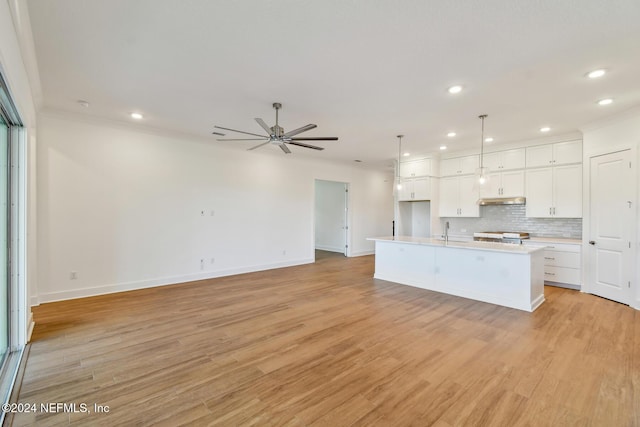 kitchen featuring white cabinets, decorative light fixtures, light hardwood / wood-style flooring, and a kitchen island with sink