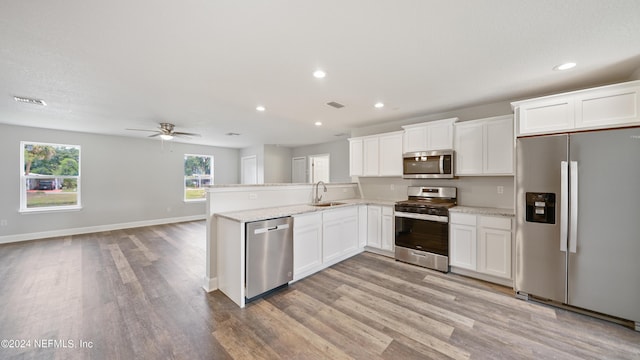 kitchen featuring sink, white cabinetry, appliances with stainless steel finishes, light hardwood / wood-style floors, and kitchen peninsula