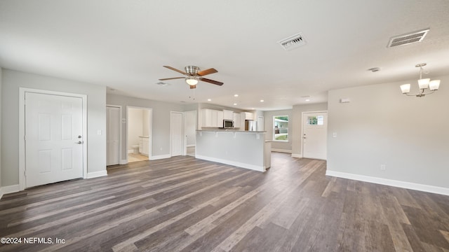 unfurnished living room featuring ceiling fan with notable chandelier and dark hardwood / wood-style floors