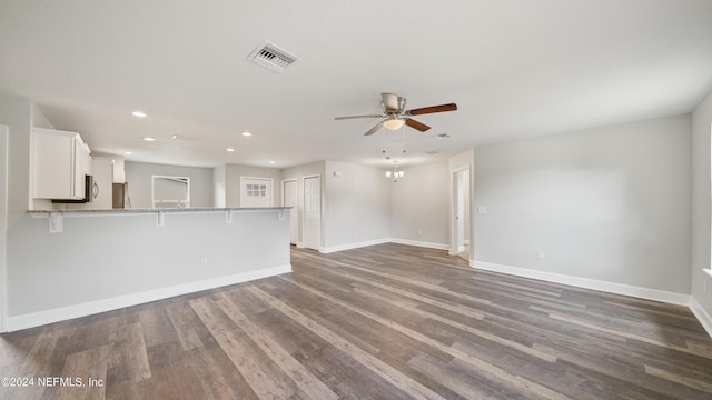 unfurnished living room with hardwood / wood-style floors and ceiling fan with notable chandelier