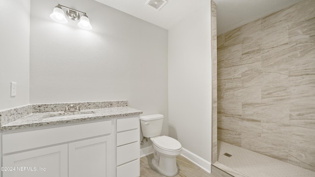 bathroom featuring a tile shower, vanity, and toilet