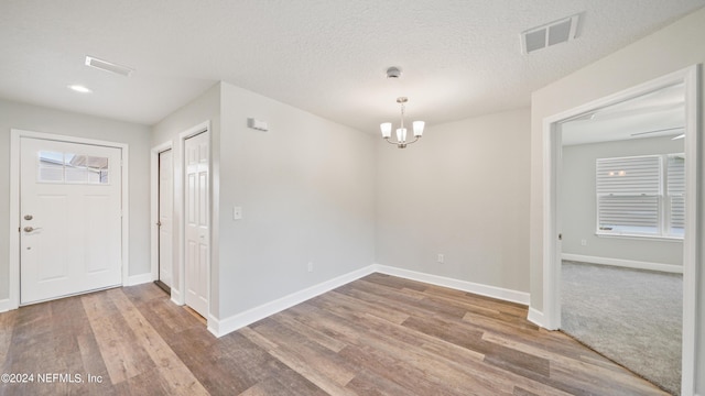 foyer entrance featuring hardwood / wood-style flooring, a textured ceiling, and a chandelier