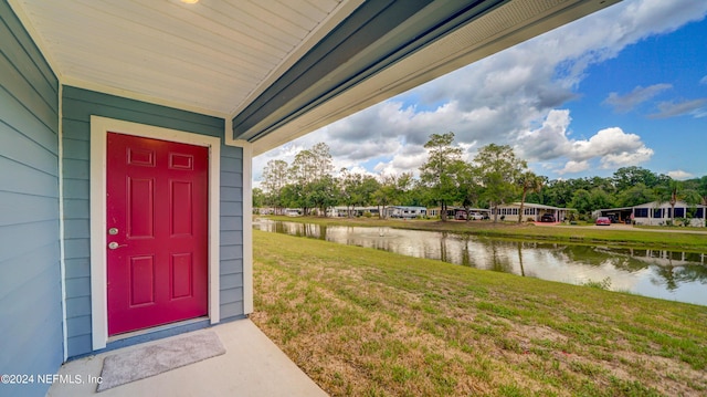 view of exterior entry with a yard and a water view