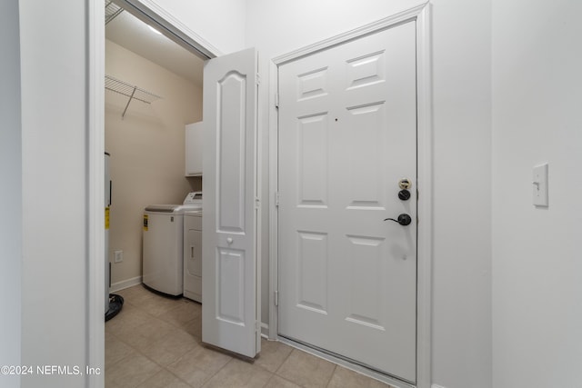 laundry area with light tile patterned floors, washing machine and dryer, and cabinets