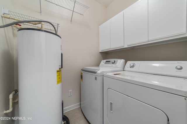 laundry area with light tile patterned floors, cabinets, washing machine and dryer, and water heater