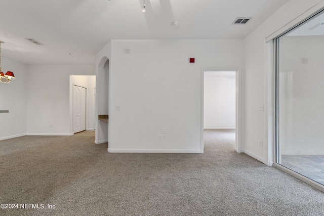 spare room with light colored carpet and a chandelier