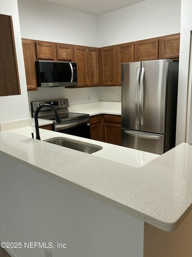 kitchen with light stone counters, kitchen peninsula, and stainless steel appliances