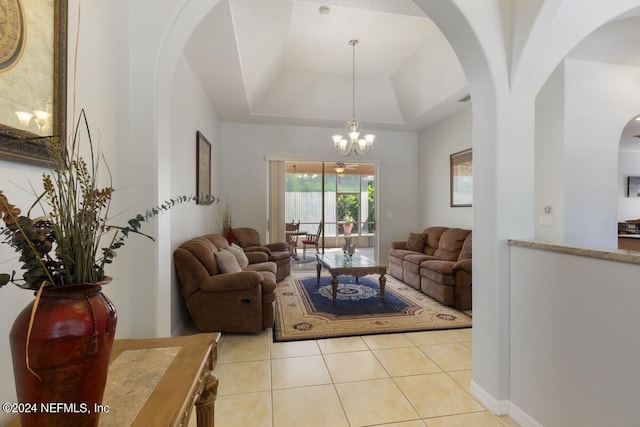 living room with a tray ceiling, light tile patterned flooring, and a chandelier