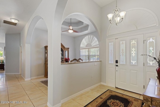 tiled entrance foyer featuring ceiling fan with notable chandelier