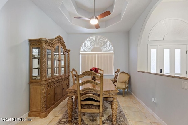 dining area featuring ceiling fan, a raised ceiling, and light tile patterned floors