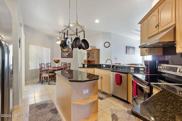 kitchen with kitchen peninsula, sink, light tile patterned floors, and appliances with stainless steel finishes