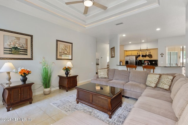 tiled living room featuring ceiling fan and a tray ceiling