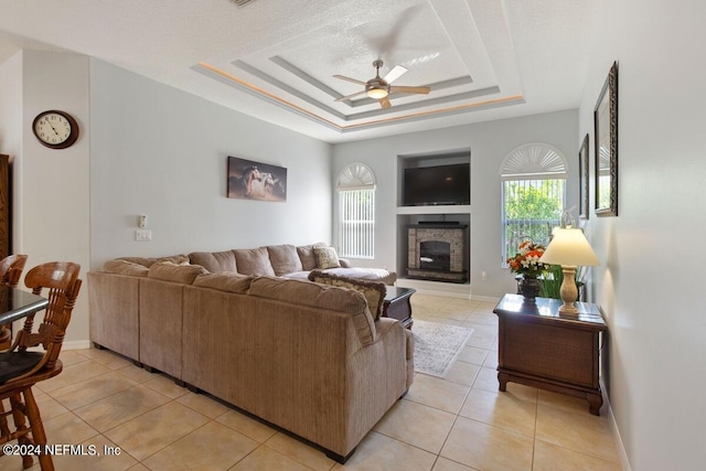 living room featuring light tile patterned floors, a tray ceiling, and ceiling fan