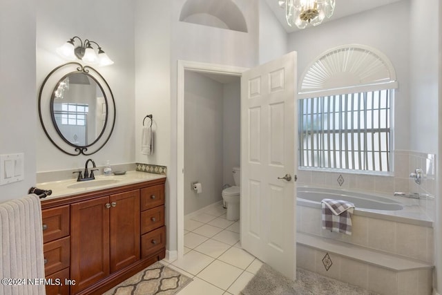 bathroom featuring tile patterned flooring, a relaxing tiled tub, a notable chandelier, toilet, and vanity