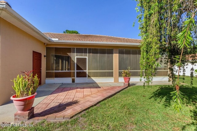 exterior space featuring a sunroom, a yard, and a patio