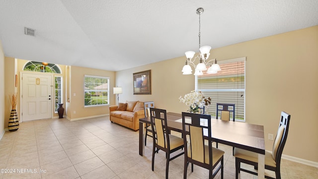 tiled dining space featuring a notable chandelier and a textured ceiling