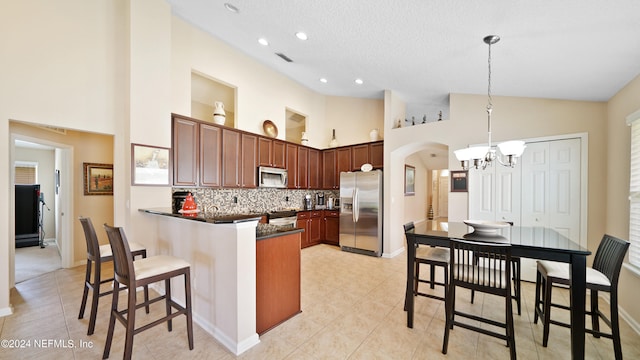 kitchen featuring stainless steel appliances, decorative light fixtures, backsplash, light tile floors, and high vaulted ceiling