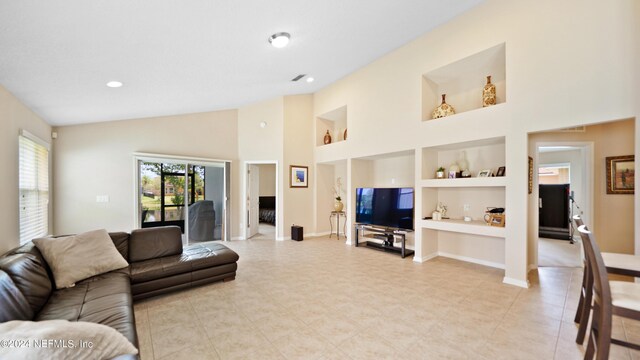 tiled living room with high vaulted ceiling and built in shelves